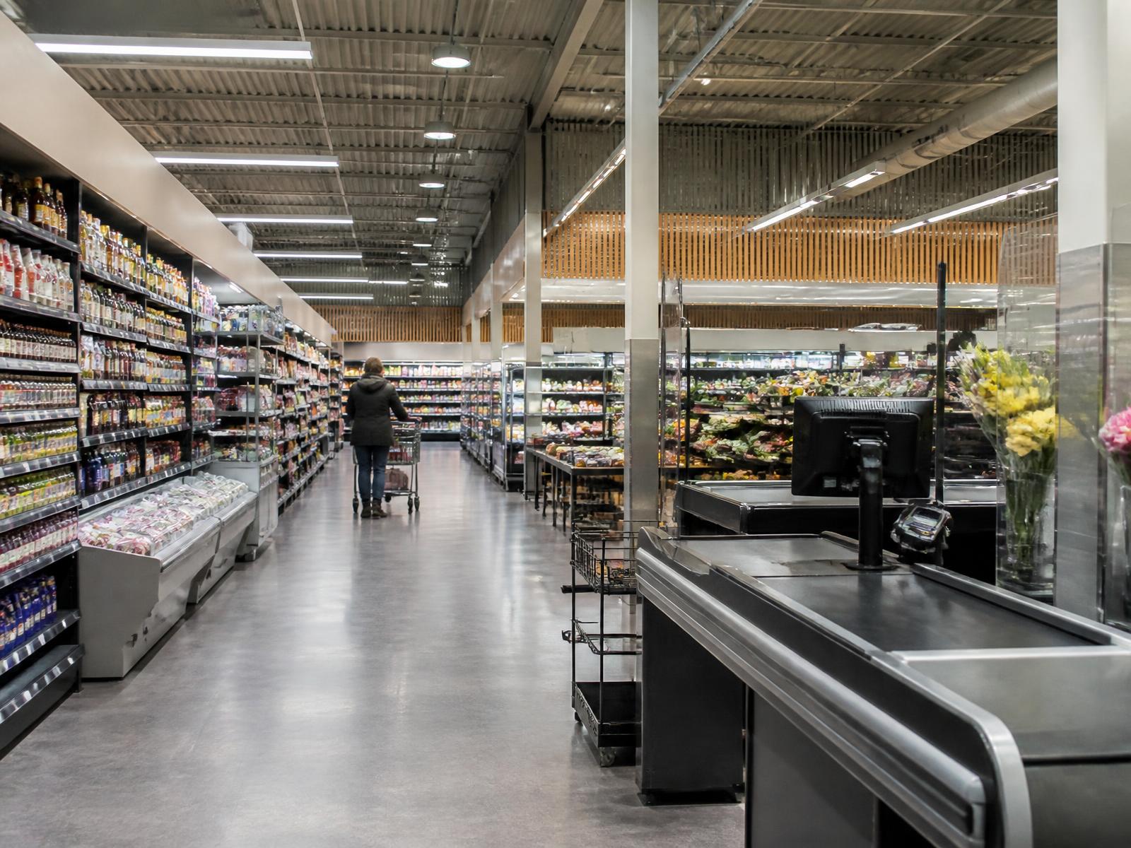 Supermercado abastecido e pronto, com pouco movimento de clientes.